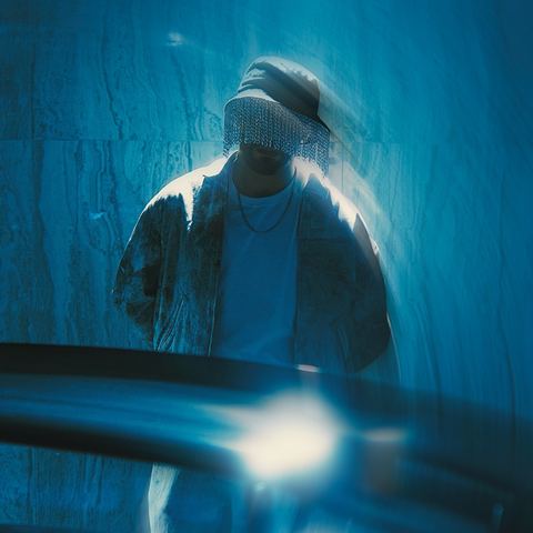 Manos in the chain-fringe mask against a marble wall, MKHADDAR promo shoot.